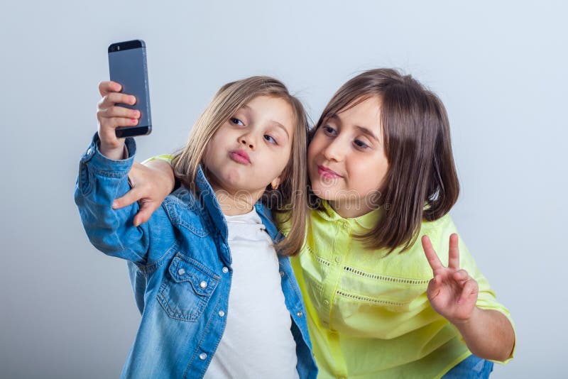 Due sorelle che posano e che prendono i selfies nello studio immagini stock