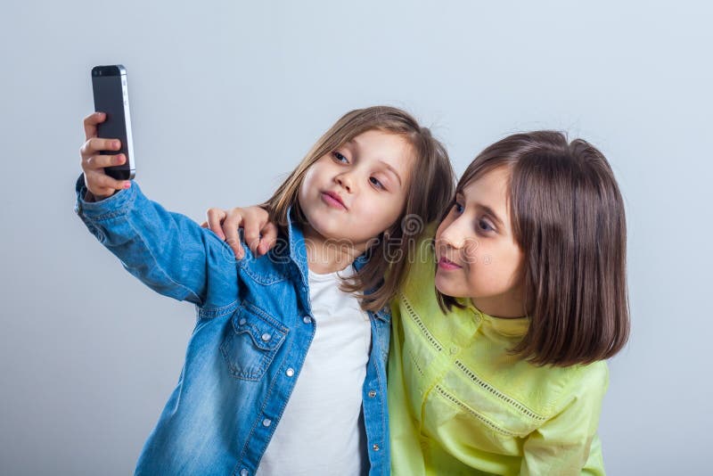 Due sorelle che posano e che prendono i selfies nello studio immagini stock