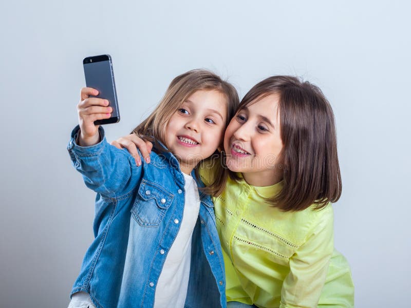 Due sorelle che posano e che prendono i selfies nello studio immagine stock