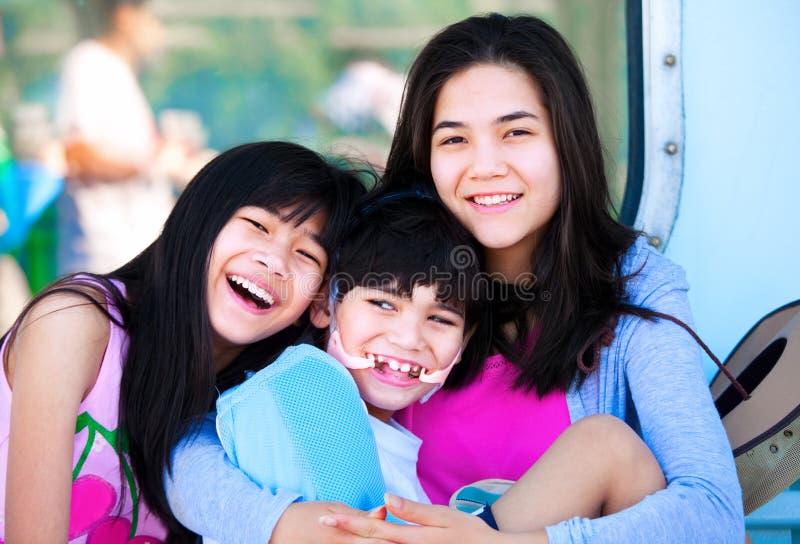 Due sorelle che prendono cura del fratello piccolo disabile fotografie stock libere da diritti Due sorelle che prendono cura del fratello piccolo disabile fotografie stock libere da diritti