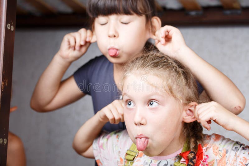 Two sisters smile and fool around teasing each other, children indulge and croak in the bedroom. Two sisters smile and fool around teasing each other, children indulge and croak in the bedroom