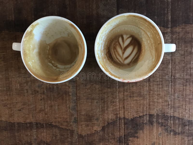 Due tazze del caffè caldo finito del latte con arte rimanente del latte immagine stock libera da diritti Due tazze del caffè caldo finito del latte con arte rimanente del latte immagine stock libera da diritti