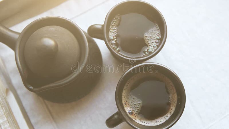 Due tazze di caffè nero e ibrik dell'argilla sul vassoio di legno