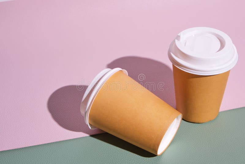 Due tazze usa e getta per il caffè caldo e il tè su fondo rosa verde e tendenza dei cibi da cucina immagine stock