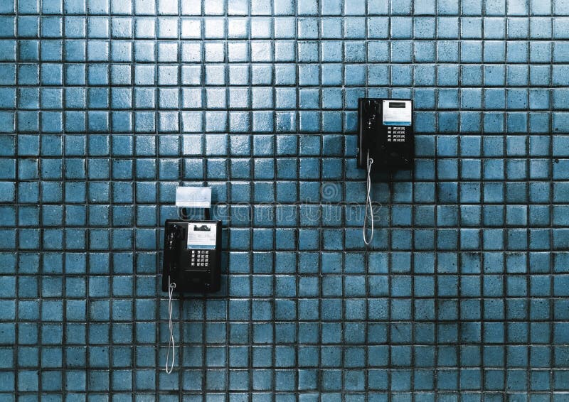 Due telefoni pubblici su una parete piastrellata immagini stock Due telefoni pubblici su una parete piastrellata immagini stock