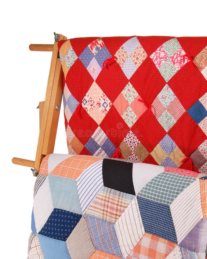 Detail view of two multicolor quilts hanging on a wooden display rack. Detail view of two multicolor quilts hanging on a wooden display rack.