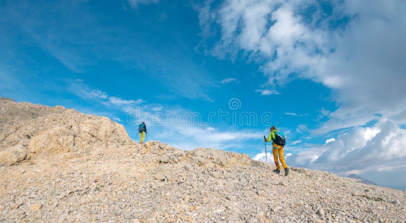 Due turisti con zaini in montagna. i turisti attraversano le montagne rocciose. riposo attivo durante l'escursionismo in montagna. immagini stock