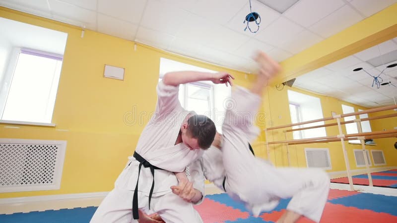 Due uomini atletici che preparano le loro abilità di aikidi nello studio Neutralizzando l'oppositore e lancio lui sul pavimento