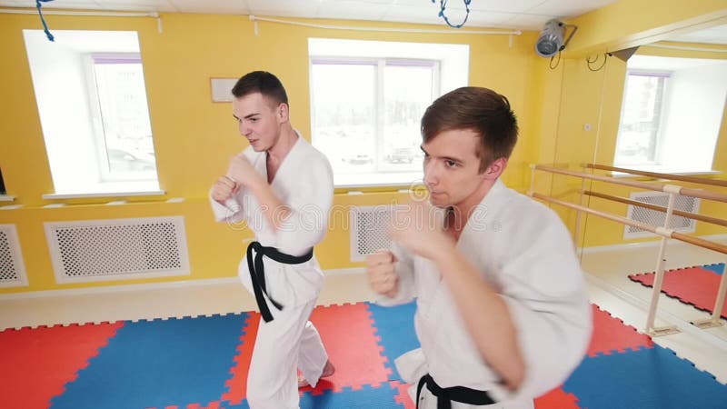 Due uomini che preparano le loro abilità di aikidi nello studio Formazione dei loro fistfights Colpire l'aria con i loro pugni