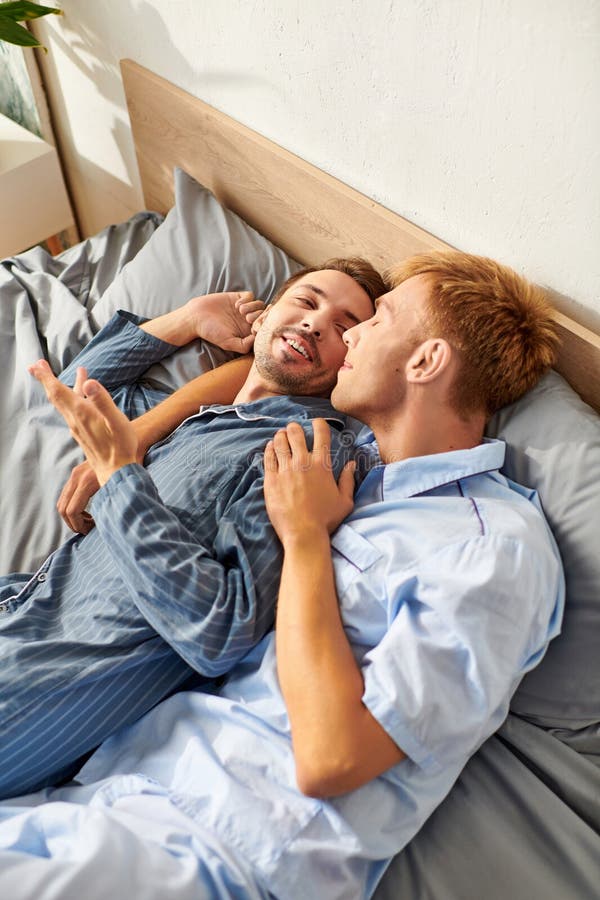 Due uomini condividono una mattinata gioiosa in pigiama godendosi l'un l'altro risate e abbracci caldi nella foto di un letto