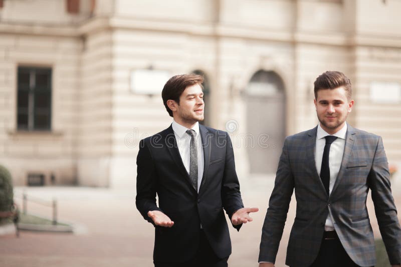 Due uomini d'affari alla moda che parlano e che sorridono all'aperto fotografia stock Due uomini d'affari alla moda che parlano e che sorridono all'aperto fotografia stock
