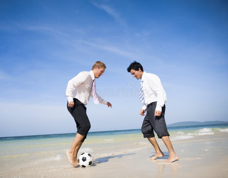 Due uomini d'affari che giocano a calcio sulla spiaggia immagine stock libera da diritti Due uomini d'affari che giocano a calcio sulla spiaggia immagine stock libera da diritti