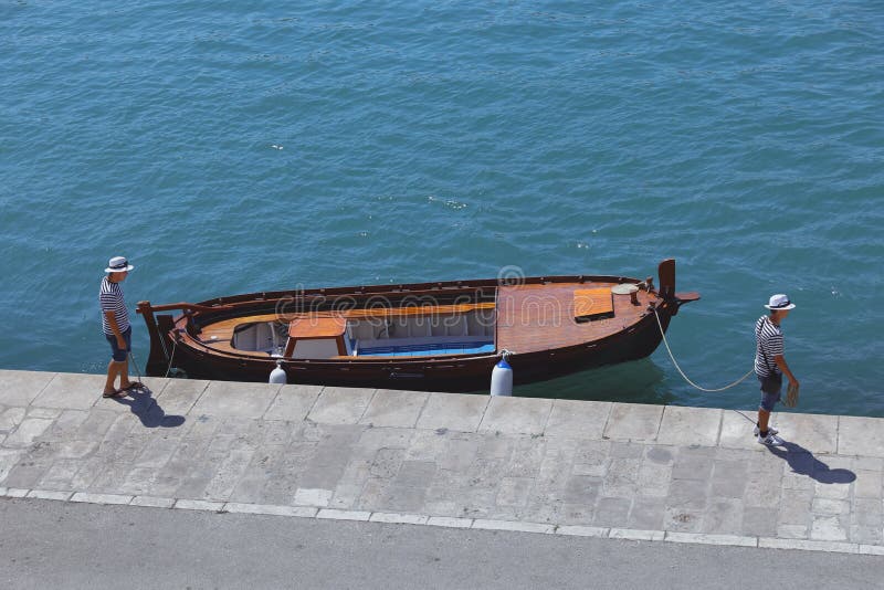 Due uomini dei marinai e la barca al molo blu scuro nella spaccatura fotografie stock libere da diritti Due uomini dei marinai e la barca al molo blu scuro nella spaccatura fotografie stock libere da diritti