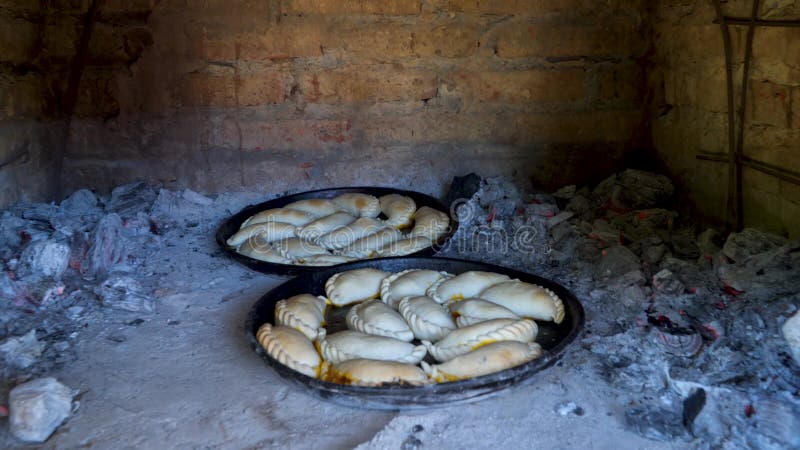 Due vassoi con le tradizionali empanadas argentine che cucinano all'interno di un forno di argilla.