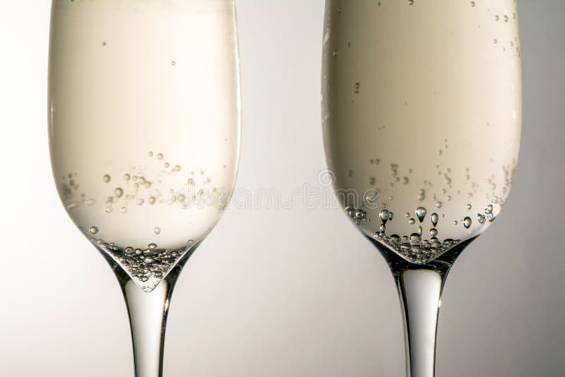 Due vetri della fine del vino del champagne su, bolle, su fondo grigio immagini stock libere da diritti Due vetri della fine del vino del champagne su, bolle, su fondo grigio immagini stock libere da diritti