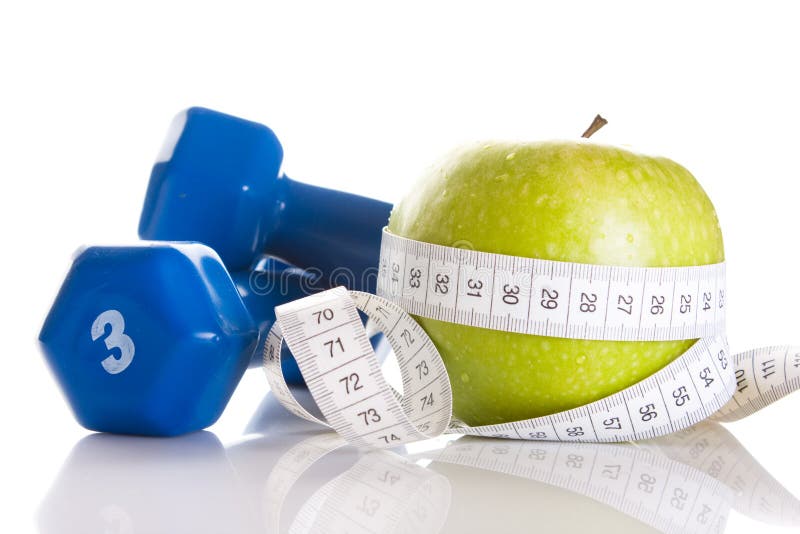 Dumbbells, fresh green apple and measure tape stock image