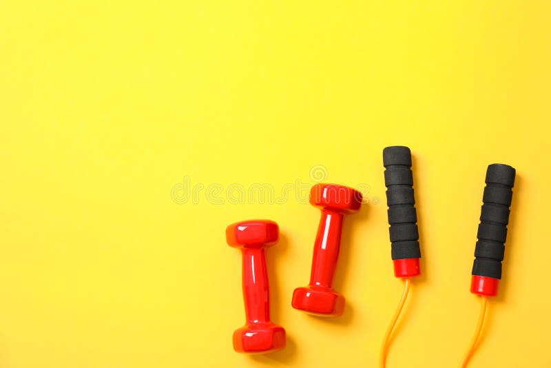 Dumbbells and jump rope on yellow background stock photo Dumbbells and jump rope on yellow background stock photo