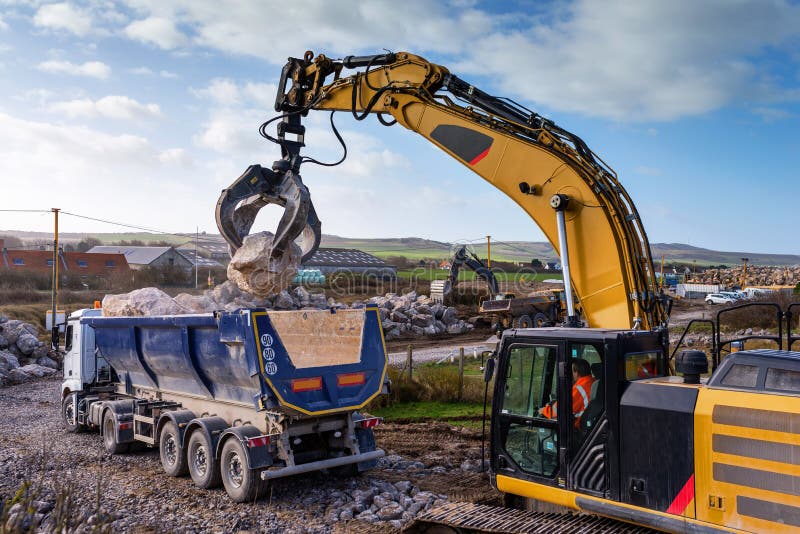 Dump Truck Unloading Its Cargo on a Construction Site with the Help of an Excavator Equipped