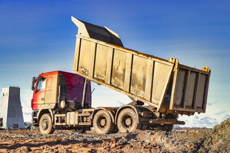 Dump Truck with a Raised Body at a Construction Site. the Process of