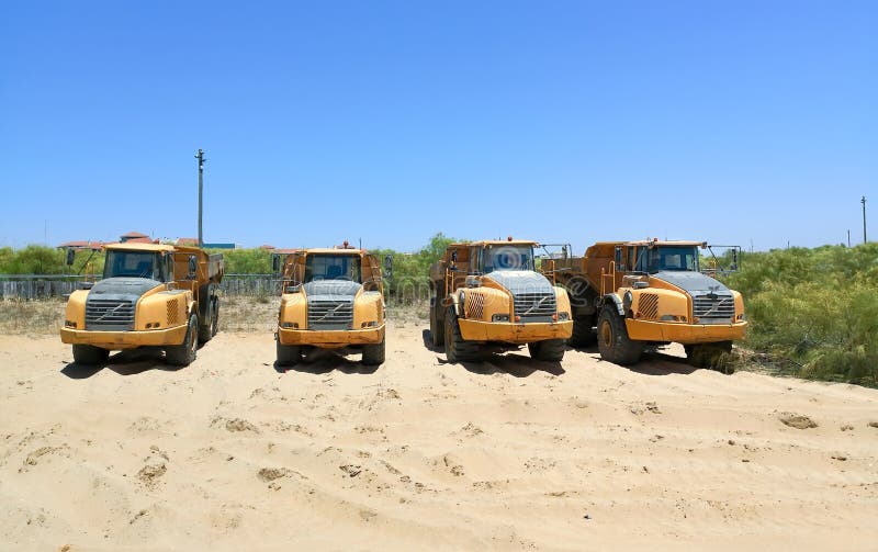 Dump Trucks Parked in the Sand Ready for Maintenance Work on the Beach