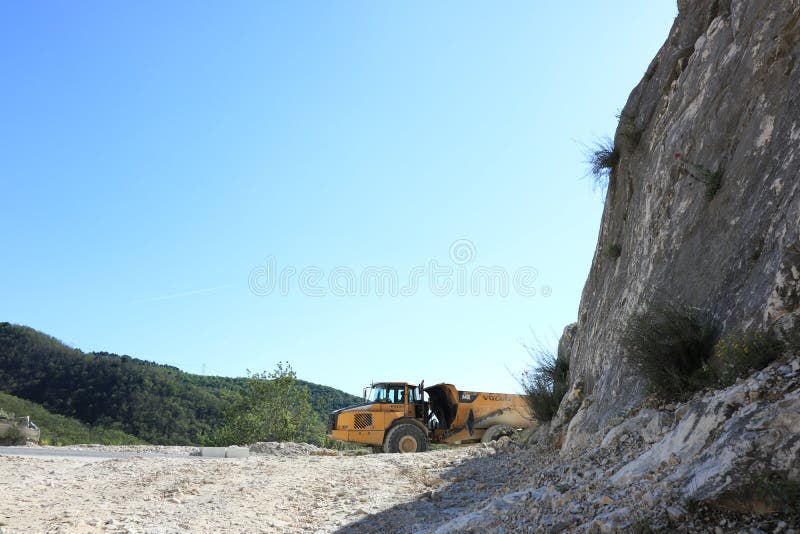 Carrara, Italy. 05/31/2019. A dumper truck used in a Carrara marble quarry. Large yellow dump truck with body. Carrara, Italy. 05/31/2019. A dumper truck used in a Carrara marble quarry. Large yellow dump truck with body