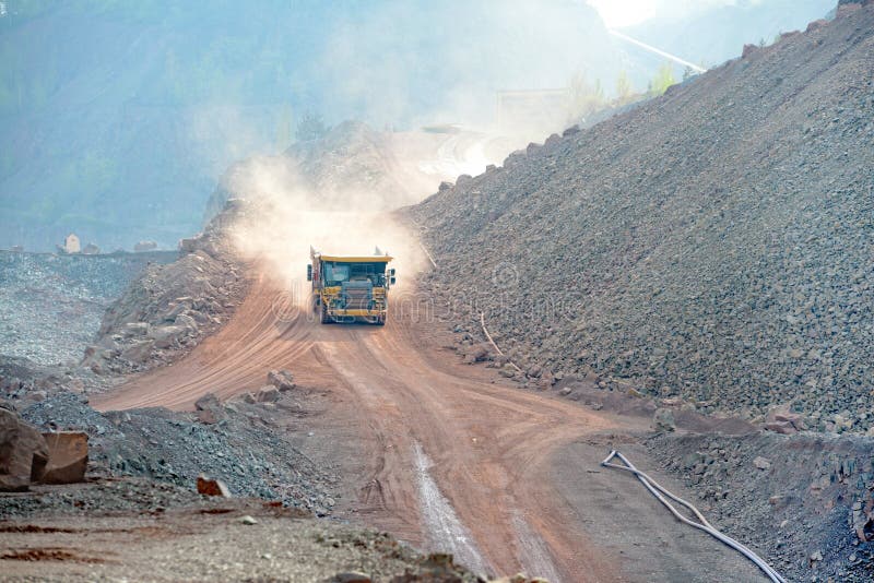 Dumper truck driving in an active quarry mine of porphyry rocks. digging. Dumper truck driving in an active quarry mine of porphyry rocks. digging