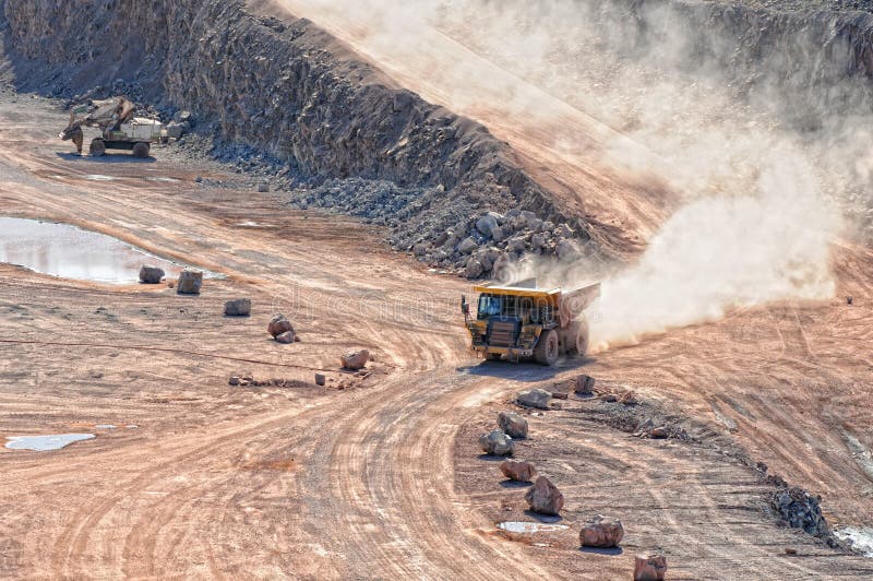 Dumper truck driving in an active quarry mine of porphyry rocks. digging. Dumper truck driving in an active quarry mine of porphyry rocks. digging