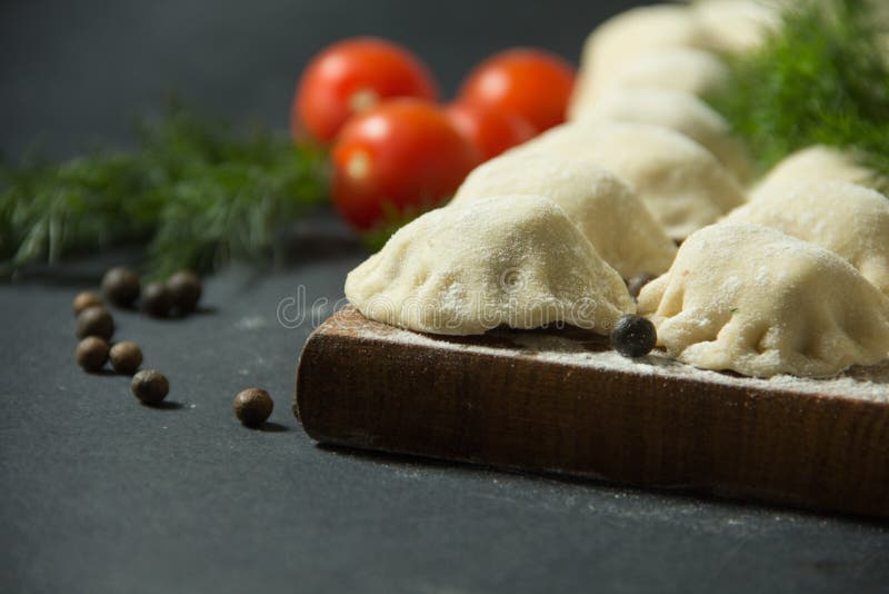 Dumplings on a Black Background with Fresh Herbs and Vegetables. Homemade Food. Traditional