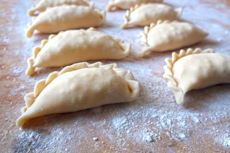 Dumplings close-up, filled with cottage cheese dumplings or pies, traditional cuisine, pastries, sprinkled with flour