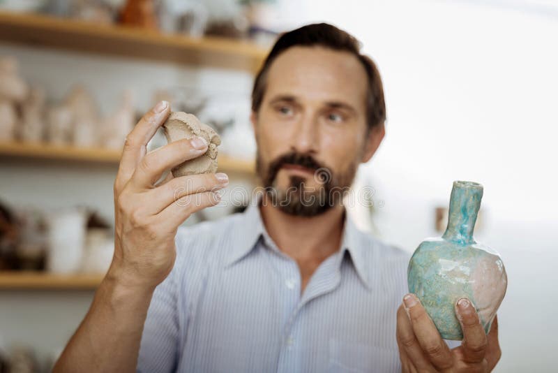 Dunkelhaariges handicraftsman, das Handvoll Töpferware hält lizenzfreie stockfotos Dunkelhaariges handicraftsman, das Handvoll Töpferware hält lizenzfreie stockfotos