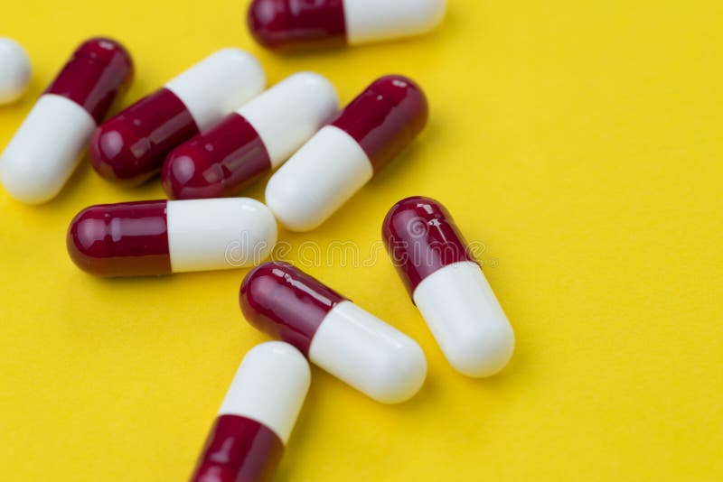 Dunkelrot und Weiß kapselt Pillen auf gelbem Hintergrund mit Kopie ein lizenzfreies stockbild Dunkelrot und Weiß kapselt Pillen auf gelbem Hintergrund mit Kopie ein lizenzfreies stockbild
