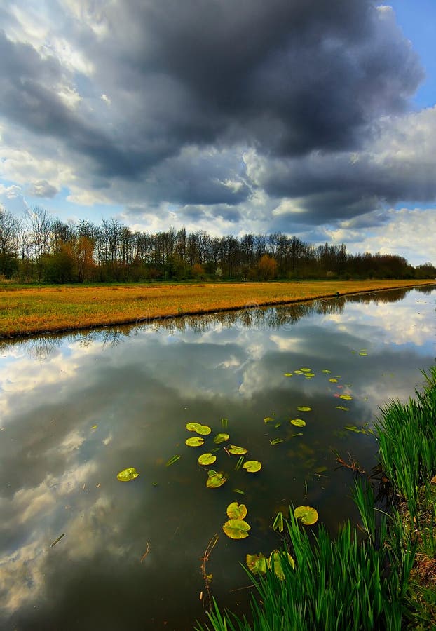 This was taken at a canal leading to Delft, the Netherlands. There were dark clouds that were reflected in the calm water. This was taken at a canal leading to Delft, the Netherlands. There were dark clouds that were reflected in the calm water.