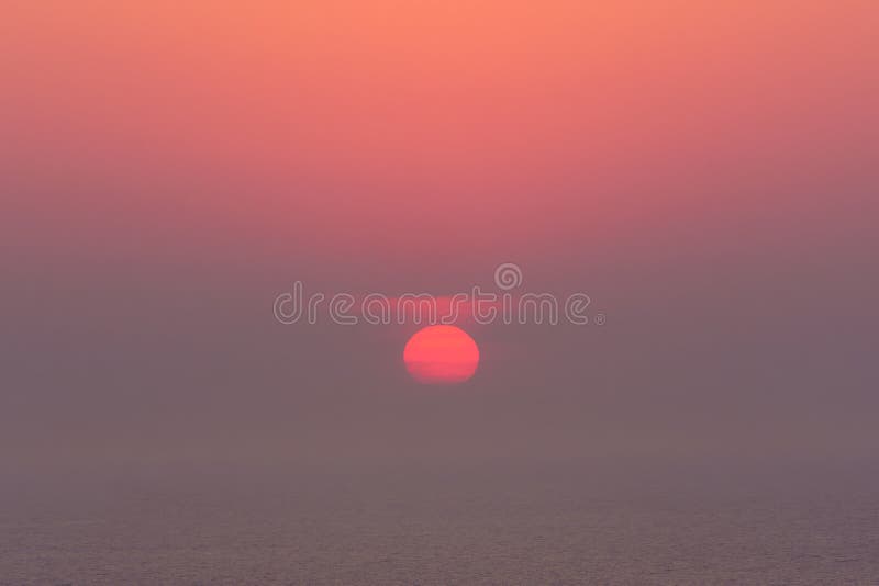 Dunstiger Sonnenuntergang auf dem Meer mit roter Sonne lizenzfreie stockfotografie Dunstiger Sonnenuntergang auf dem Meer mit roter Sonne lizenzfreie stockfotografie