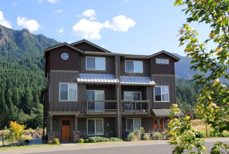 Front view of a new three story duplex dwelling in the mountains, either for homes, or for vacation homes. Territorial view in background, blue skies. Front view of a new three story duplex dwelling in the mountains, either for homes, or for vacation homes. Territorial view in background, blue skies.