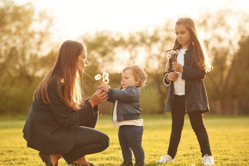 Durch Sonnenlicht erhellt. Kronleuchter. Frau mit ihren zwei jungen Töchtern ist auf dem Sommerfeld stockbild