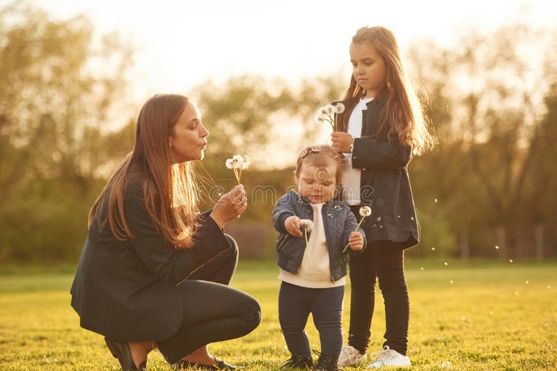Durch Sonnenlicht erhellt. Kronleuchter. Frau mit ihren zwei jungen Töchtern ist auf dem Sommerfeld stockbild
