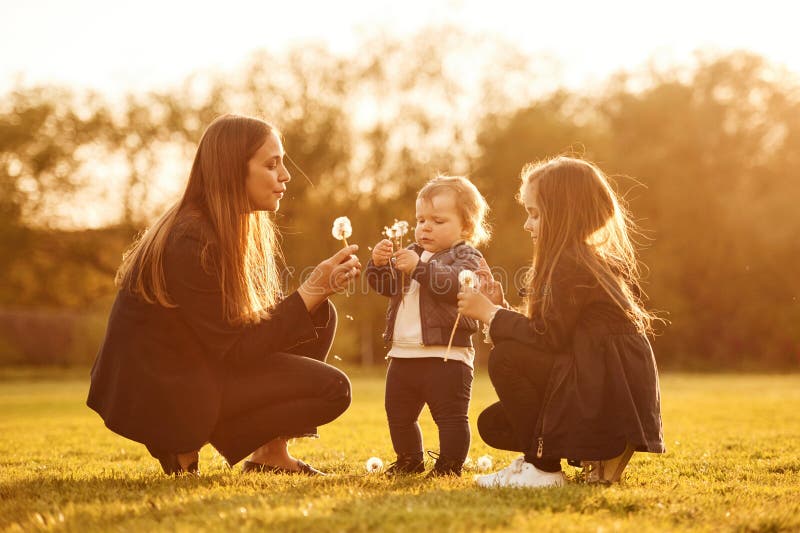 Durch Sonnenlicht erhellt. Kronleuchter. Frau mit ihren zwei jungen Töchtern ist auf dem Sommerfeld lizenzfreies stockbild
