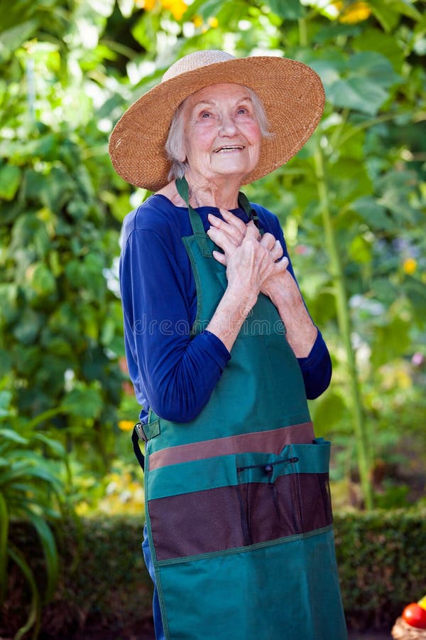 Durchdachte ältere Frau im Garten-Hut und dem Schutzblech stockfotos Durchdachte ältere Frau im Garten-Hut und dem Schutzblech stockfotos