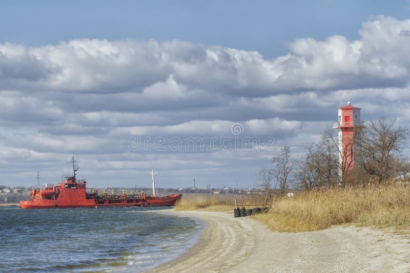 Durchläufe eines große Frachtschiffs nahe dem Leuchtturm zum Hafen eines Containerbahnhofs im Mykolaiv-Seehafen stockbilder Durchläufe eines große Frachtschiffs nahe dem Leuchtturm zum Hafen eines Containerbahnhofs im Mykolaiv-Seehafen stockbilder