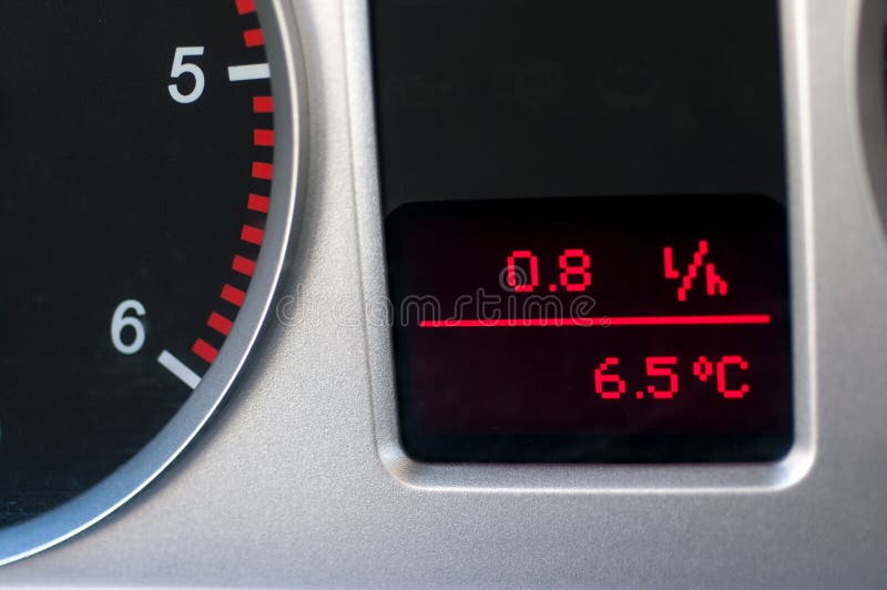 Average fuel consumption and a thermometer in used family car dashboard close up shot. Average fuel consumption and a thermometer in used family car dashboard close up shot.