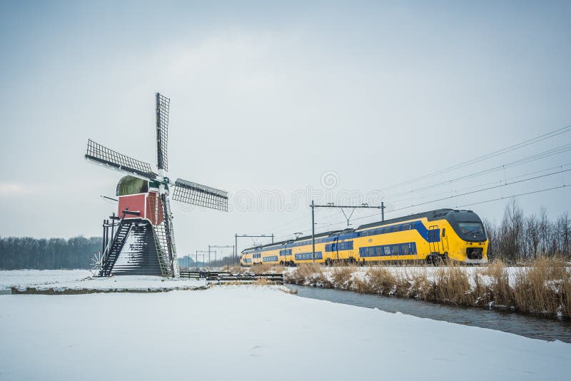 Dutch train and windmill in winter landscape