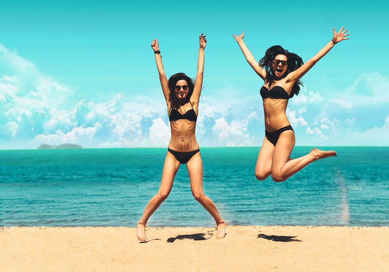 Two Attractive Girls in Bikinis Jumping on the Beach. Best Friends Having Fun, Summer vacation holiday Lifestyle. Happy women jumping freedom on white sand. Two Attractive Girls in Bikinis Jumping on the Beach. Best Friends Having Fun, Summer vacation holiday Lifestyle. Happy women jumping freedom on white sand.