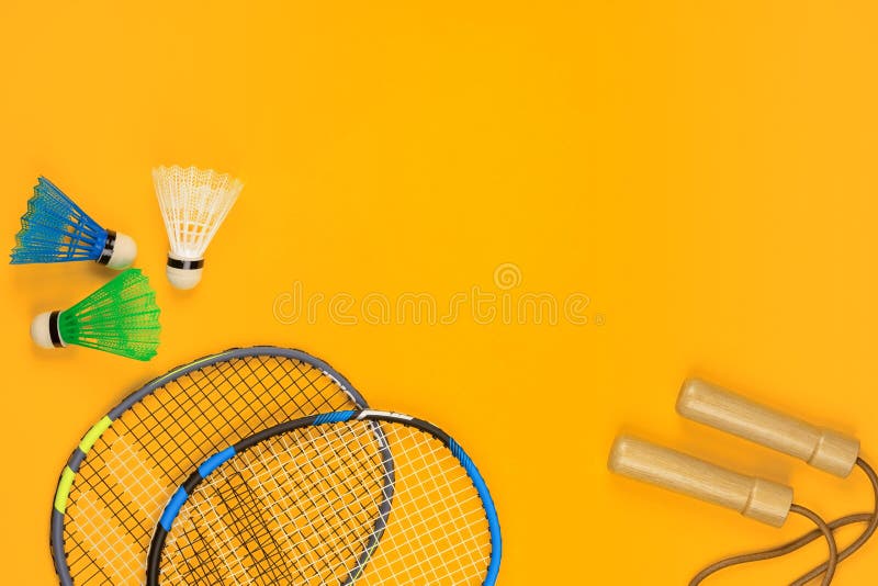 Dwa badminton kanta i dwa shuttlecocks obok skok arkany na żółtym tle obraz stock Dwa badminton kanta i dwa shuttlecocks obok skok arkany na żółtym tle obraz stock
