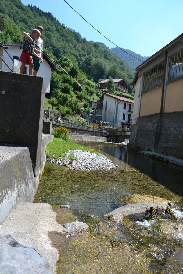 Lecco/Italy - August 1, 2013: Two boys are fishing in the mountain stream with fishing rod. Lecco/Italy - August 1, 2013: Two boys are fishing in the mountain stream with fishing rod.