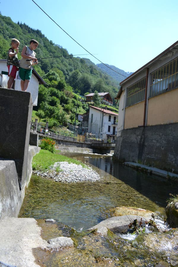 Lecco/Italy - August 1, 2013: Two boys are fishing in the mountain stream with fishing rod. Lecco/Italy - August 1, 2013: Two boys are fishing in the mountain stream with fishing rod.