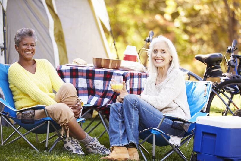 Two Mature Women Relaxing On Camping Holiday Smiling To Camera. Two Mature Women Relaxing On Camping Holiday Smiling To Camera