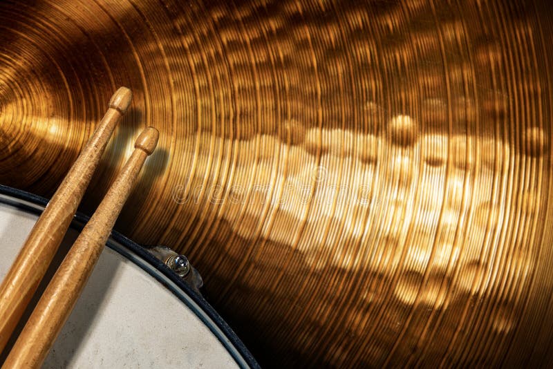 Dwa drewniane pałeczki bębnowe na bębnie snare i złoty cymbał - instrument perkusyjny