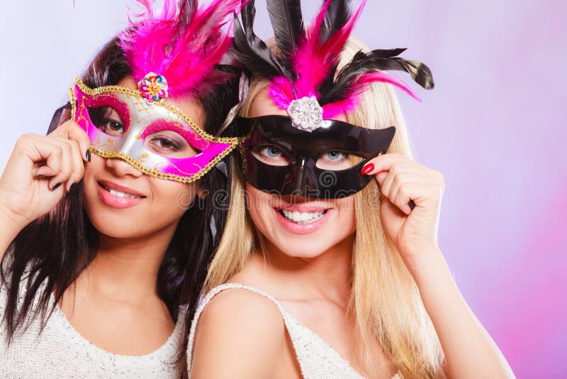 Holidays, people and celebration concept. two women mixed race and caucasian with carnival venetian masks over festive background. Holidays, people and celebration concept. two women mixed race and caucasian with carnival venetian masks over festive background.