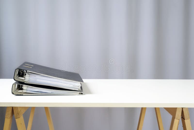 Dwa kołowe segregatory leżące na prostym białym biurku na drewnianych stojakach, szare tło z przestrzenią kopiowania, koncepcją b