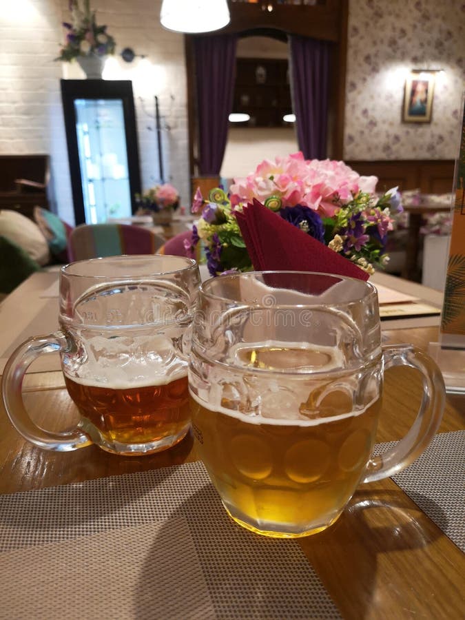 Dwa kubka piwna pozycja na stołowym zmroku i światło na tle piękny wnętrze café obrazy stock